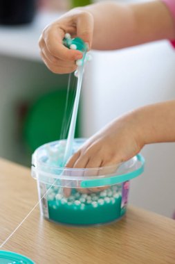 A child playing with bright, blue slime, enjoying a fun and creative indoor activity. Childhood, craft. clipart