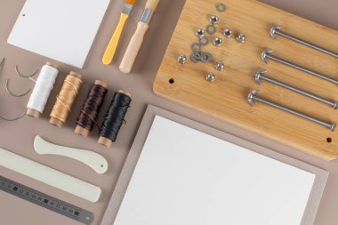 İplik fırçaları ve gri arkaplandaki aletleri kesen yapıştırma kitabı kiti. Kağıt aksesuarlar için el işi hobi malzemeleri. Yaratıcı boş zaman aktivitesi