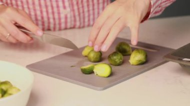 Bir kadın mutfakta Brüksel lahanası kesiyor. Sebze ve vejetaryen yemekleri pişirme süreci.