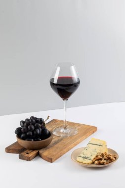 Üzüm kümesi peynirli doğal kırmızı şarap ve beyaz arka planda fındık. Sofrada gurme atıştırmalıklarıyla servis edilen alkollü şenlik içeceği. Şarap sunumu