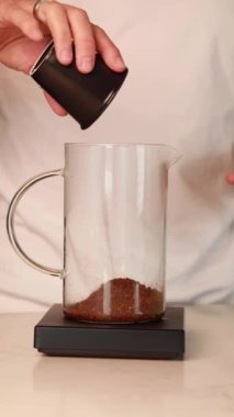 Fransız makinesine taze kahve dolduran bir adam lezzetli bir fincan kahve demlemeye hazırlanıyor.