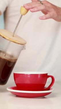 Bir el ustalıkla zengin kahveyi bir Fransız makinesinden alıp şık bir tezgahın üzerine yerleştirilmiş parlak ve canlı kırmızı bardaklara dolduruyor.