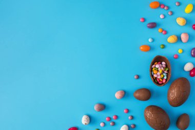 Çikolatalı Paskalya yumurtası. Mavi arka planda renkli rüzgarlar var. Mutlu Paskalyalar konsepti. Boşluğu kopyala