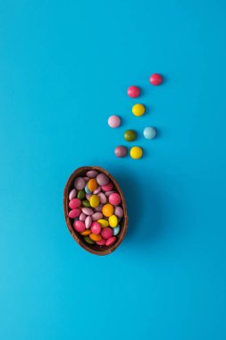 Çikolatalı Paskalya yumurtası. Mavi arka planda renkli rüzgarlar var. Mutlu Paskalyalar konsepti.