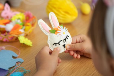 Paskalya işçiliği, keçeli tavşan ve çocuklar için renkli süslemeler. Paskalya tavşanı keçeden yapılmış, kendi elleriyle bir kızın elinde. ÇEVİR