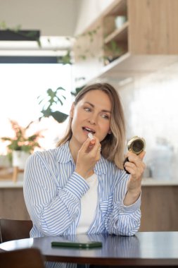 Kadın, doğal görünümlü günlük makyaj için evde ruj sürüyor. Kozmetik