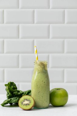 Taze yeşil smoothie ile kivi ve beyaz arka planda elma. Detoks kavramı, vejetaryen yemeği.