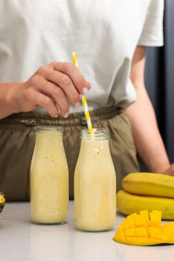 Sağlıklı yaşam ve yaz titreşimleri için çizgili saman ve taze malzemelerle mango muzlu smoothie tazeliyorum. Detoks kavramı