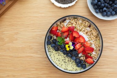 Tahta masada taze meyve ve chia çekirdekli sağlıklı kahvaltı avokado smoothie kasesi. Vejetaryen yemeği