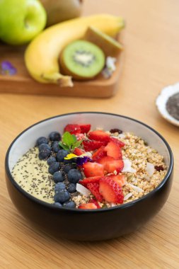 Tahta masada taze meyve ve chia çekirdekli sağlıklı kahvaltı avokado smoothie kasesi. Vejetaryen yemeği