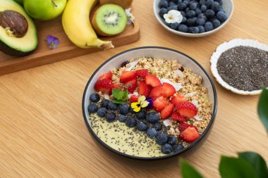Tahta masada taze meyve ve chia çekirdekli sağlıklı kahvaltı avokado smoothie kasesi. Vejetaryen yemeği