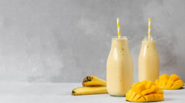 Gri arka planda taze meyve garnitürlü tropikal mango ananas kokteyli. Detoks kavramı. Banner, boşluğu kopyala