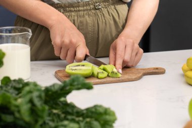 Modern bir mutfak ortamında sağlıklı bir smoothie için taze kivi dilimleri hazırlıyorum. Meyve.