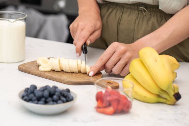 Muz kesen kadın. Taze meyve ve sütle sağlıklı bir kahvaltı hazırlıyorum. Sağlıklı gıda kavramı