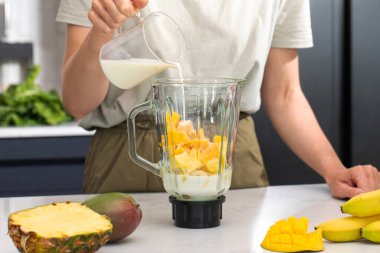 Modern bir mutfakta mango, ananas ve sütle taze tropikal meyve püresi. Detoks kavramı
