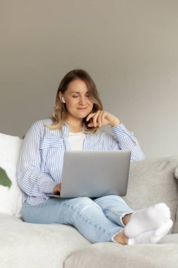 Evde dizüstü bilgisayarla eğlenen rahat bir kadın. Laptop kullanıyorum. Evde çalışıyorum.