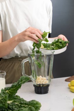 Parlak mutfak tezgahında lahana ve muzlu sağlıklı yeşil bir smoothie hazırlıyorum. Detox