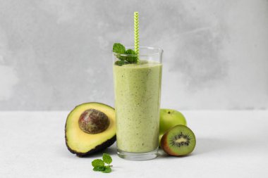 Gri arka planda avokado ve kivi ile yeşil smoothie tazeleniyor. Detoks kavramı