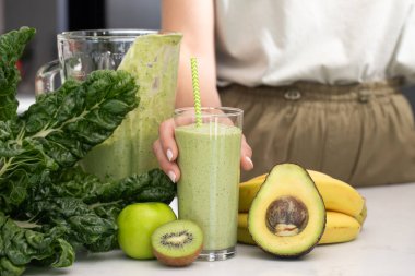 Avokado, kivi ve yeşil elmadan yapılmış yeşil smoothie ile cam tutan kadın. Detoks kavramı