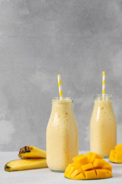 Gri arka planda taze meyve garnitürlü tropikal mango ananas kokteyli. Detoks kavramı