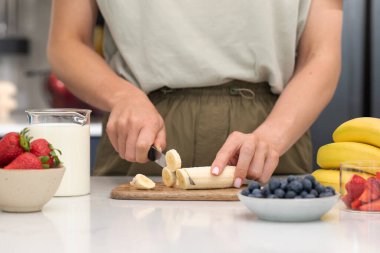 Muz kesen kadın. Taze meyve ve sütle sağlıklı bir kahvaltı hazırlıyorum. Sağlıklı gıda kavramı
