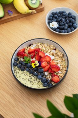 Tahta masada taze meyve ve chia çekirdekli sağlıklı kahvaltı avokado smoothie kasesi. Vejetaryen yemeği