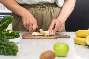 Tahtada muz kesen kadın. Meyve, sağlıklı gıda konsepti