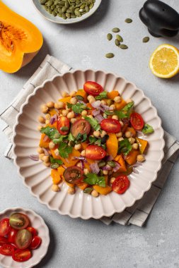 Taze nohut ve domatesli balkabağı salatası ve sağlıklı beslenmek için bitkiler. Sonbahar salatası. Sağlıklı ve vejetaryen yemeği kavramı.