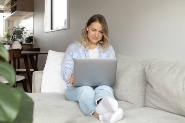 Evde dizüstü bilgisayarla eğlenen rahat bir kadın. Laptop kullanıyorum. Evde çalışıyorum.