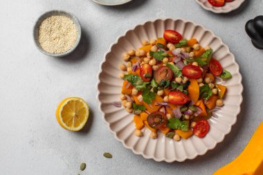 Sonbahar sıcacık bezelye ve kavrulmuş balkabağı salatası taze kiraz domatesleri ve bitkilerle birlikte. Vejetaryen ve sağlıklı salata kavramı