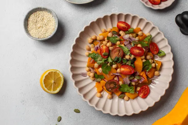 Sonbahar sıcacık bezelye ve kavrulmuş balkabağı salatası taze kiraz domatesleri ve bitkilerle birlikte. Vejetaryen ve sağlıklı salata kavramı