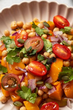 Taze nohut ve domatesli balkabağı salatası ve sağlıklı beslenmek için bitkiler. Sonbahar salatası. Sağlıklı ve vejetaryen yemeği kavramı.