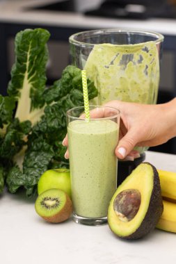 Avokado, kivi ve yeşil elmadan yapılmış yeşil smoothie ile cam tutan kadın. Detoks kavramı