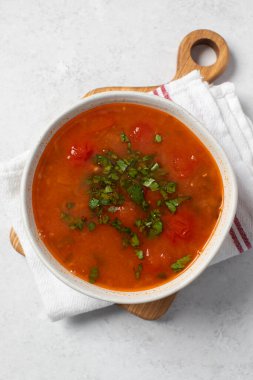 Domatesli taze sebze çorbası ve keten peçetedeki beyaz kasede otlar. Vejetaryen menüsü. 