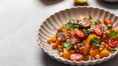 Taze nohut ve domatesli balkabağı salatası ve sağlıklı beslenmek için bitkiler. Sonbahar salatası. Sağlıklı ve vejetaryen yemeği kavramı. Boşluğu kopyala