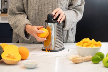 Mutfakta taze portakal ızgarası ve yemek pişirmek için meyve seçimi yapan beyaz bir yetişkin. Sağlıklı olmak ve yemek hazırlamak.