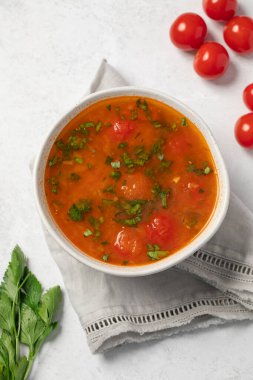 Domatesli taze sebze çorbası ve keten peçetedeki beyaz kasede otlar. Vejetaryen menüsü. 
