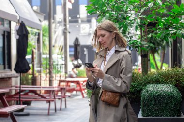 Şehir caddesinde akıllı telefon kullanan genç bir kadının şehir sahnesi. İş kadını kavramı 