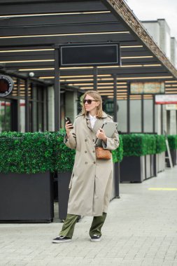 Açık havada akıllı telefon ve laptop kullanan şehirli profesyonel bir kadın. İş kadını kavramı 