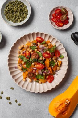 Taze nohut ve domatesli balkabağı salatası ve sağlıklı beslenmek için bitkiler. Sonbahar salatası. Sağlıklı ve vejetaryen yemeği kavramı.