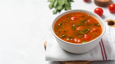 Domatesli taze sebze çorbası ve keten peçetedeki beyaz kasede otlar. Vejetaryen menüsü. Boşluğu kopyala