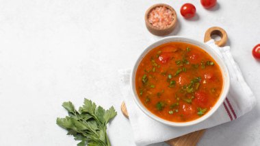 Domatesli taze sebze çorbası ve keten peçetedeki beyaz kasede otlar. Vejetaryen menüsü. Boşluğu kopyala