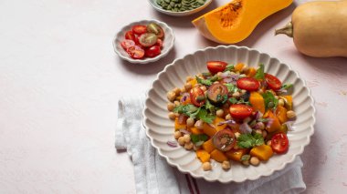 Taze nohut ve domatesli balkabağı salatası ve sağlıklı beslenmek için bitkiler. Sonbahar salatası. Sağlıklı ve vejetaryen yemeği kavramı. Boşluğu kopyala