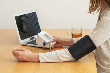 Beyaz bir kadın kan basıncını evde ölçüyor. Sağlık hizmeti kavramı