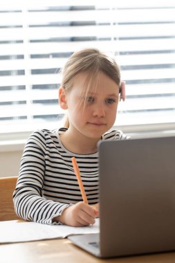 Bilgisayarla çalışan genç bir kız ve online eğitim ve öğrenim için pencerenin yanındaki not defteri. E-öğrenme kavramı