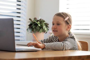 Evde çalışan, dizüstü bilgisayarın başında oturan bir çocuk. Çevrimiçi okulda okuyan tatlı bir kız. Eğitim ve e-öğrenim kavramı.
