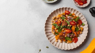 Taze nohut ve domatesli balkabağı salatası ve sağlıklı beslenmek için bitkiler. Sonbahar salatası. Sağlıklı ve vejetaryen yemeği kavramı. Boşluğu kopyala