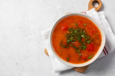 Domatesli taze sebze çorbası ve keten peçetedeki beyaz kasede otlar. Vejetaryen menüsü. Boşluğu kopyala