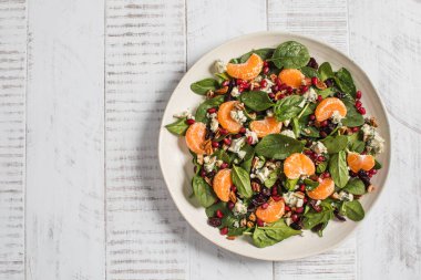 Taze ıspanak ve narlı narenciye salatası ve beyaz ahşap üzerine mavi peynir. Vejetaryenler için bayram ve Noel salatası