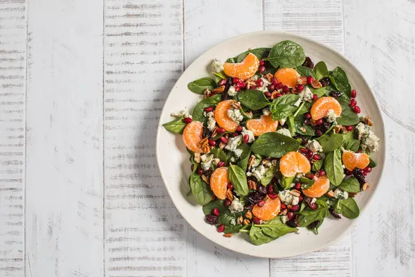Taze ıspanak ve narlı narenciye salatası ve beyaz ahşap üzerine mavi peynir. Vejetaryenler için bayram ve Noel salatası
